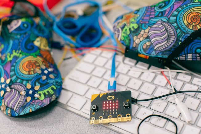 A couple of slip on shoes are attached to a micro:bit, amongst a keyboard and crocodile clips and cables