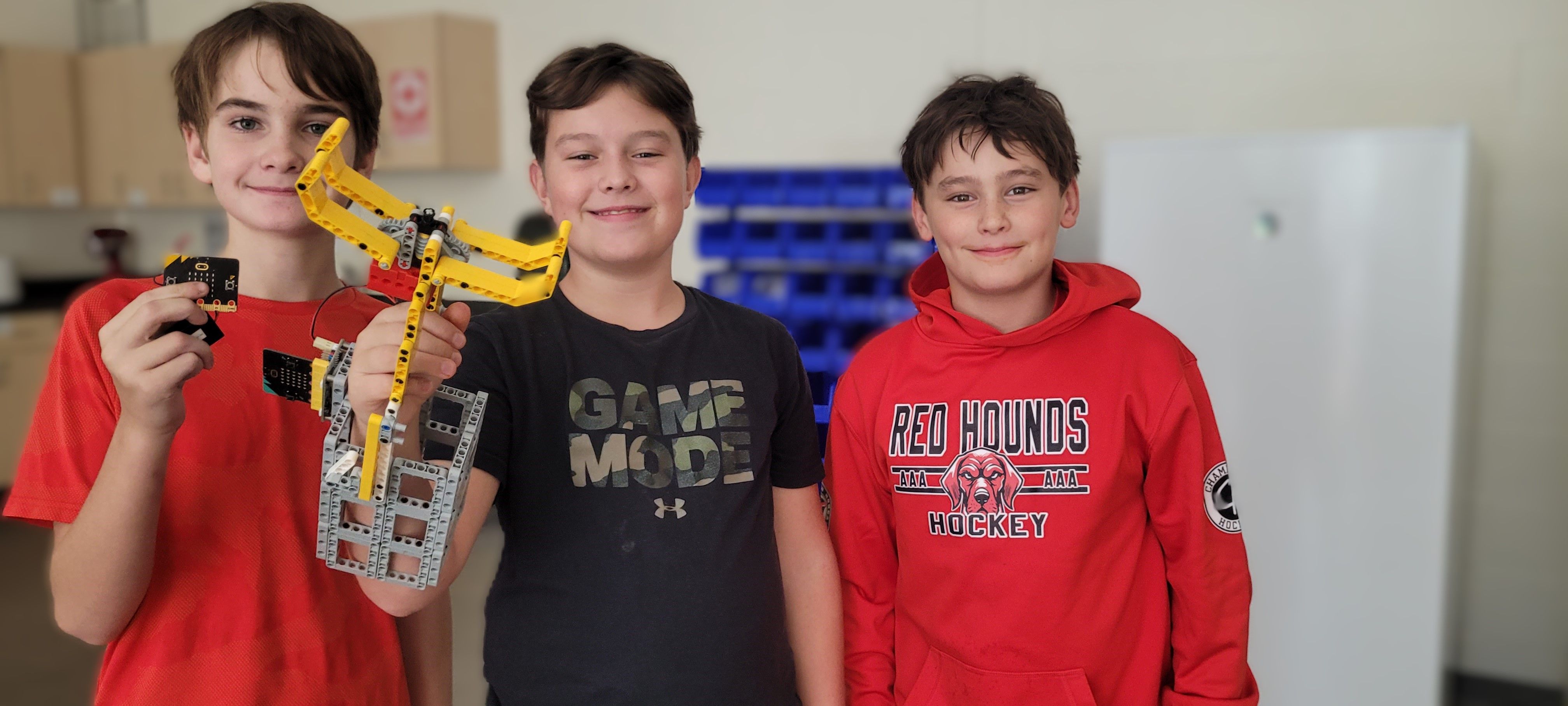 Three students pose with the robotic arm prototype.