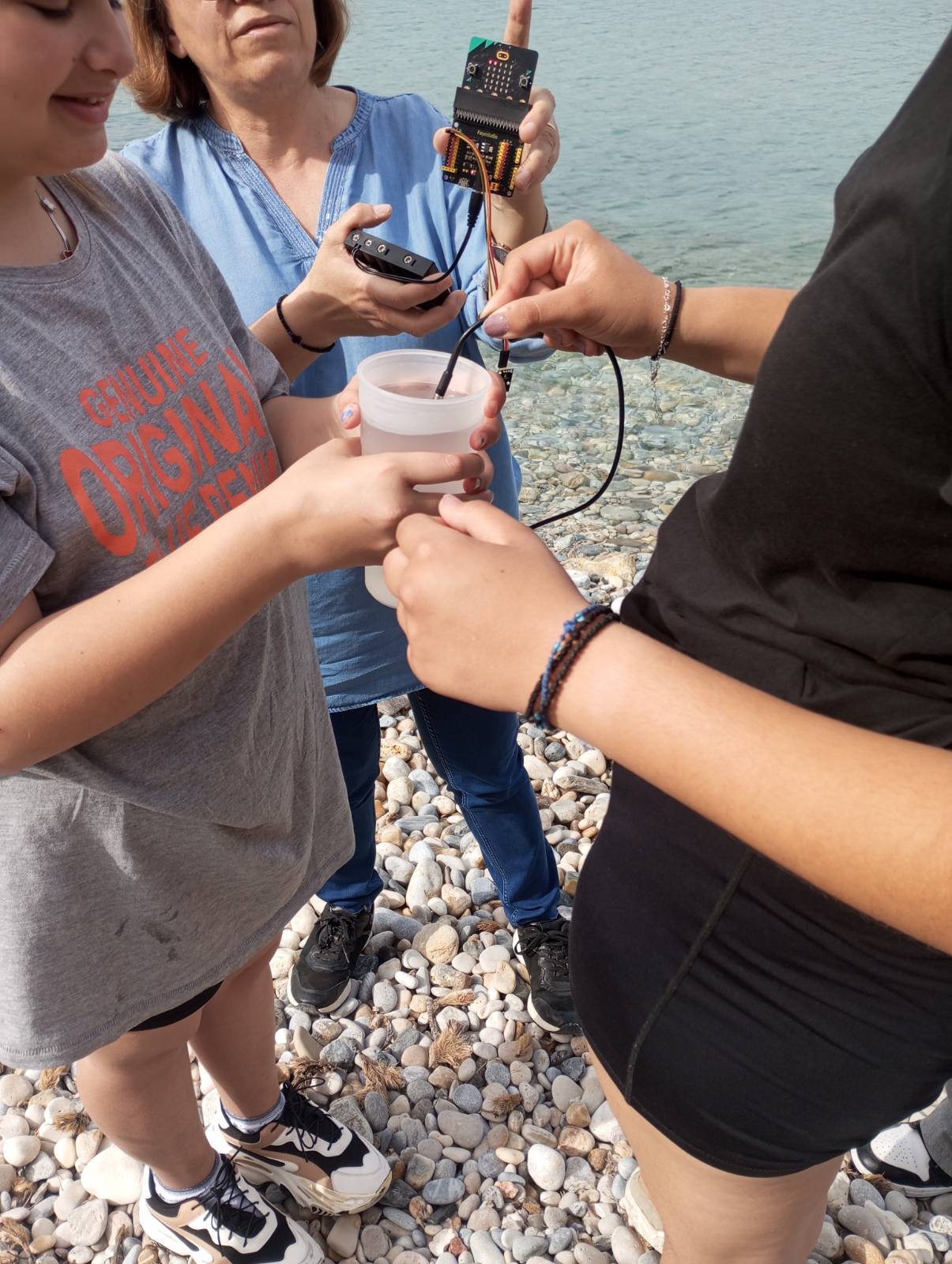 Students and teacher testing water quality, holding a micro:bit.