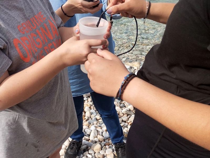 Students and teacher testing water quality, holding a micro:bit.