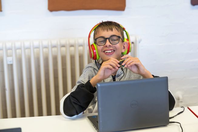 A student moving a micro:bit connected to a laptop, exploring how it responds to movement.