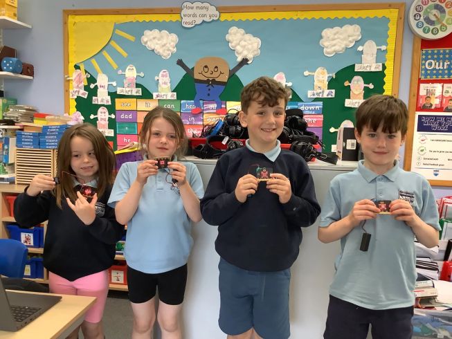 Four students from Carnalridge Primary School show off the emoji they have coded to their micro:bits