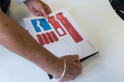 Educator placing a sheet of swell printed cut-out blocks on an adhesive magnetic sheet