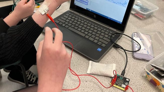 Students connect a micro:bit to a piece of foil, taped to their wrist, to measure heart rate