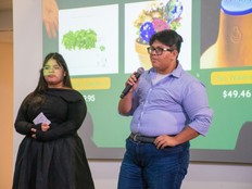 Students present their Microgarden project in front of a screen with a microphone.
