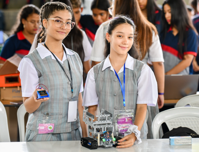 Two female students at a Colombia Codes event hold up micro:bits proudly