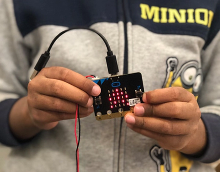 A young boy holding a micro:bit