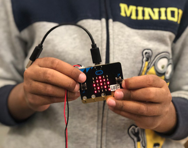 A boy holding up a micro:bit