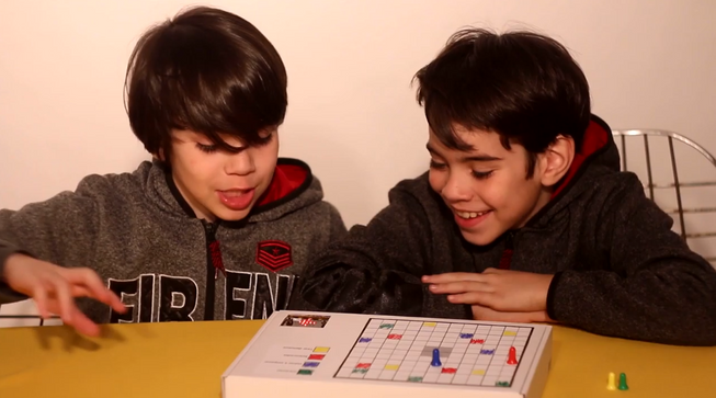 Two boys playing a board game with a micro:bit