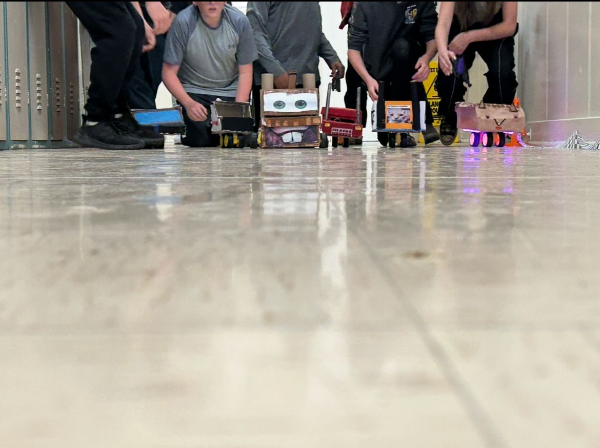 Students crouch behind their shoe box race cars.