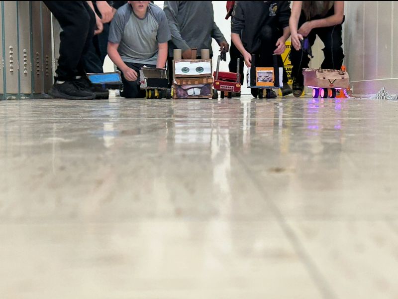 Students crouch behind their shoe box race cars.