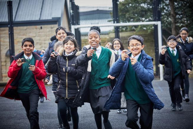 Children in coats are happily using micro:bits in the playground