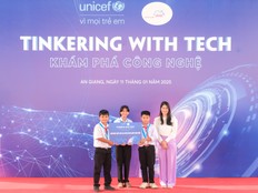 Students pose in front of a sign that says "Tinkering with Tech"