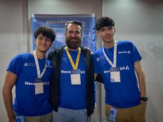 Students and teacher pose in front of a large sign for the MecaArm:bit.