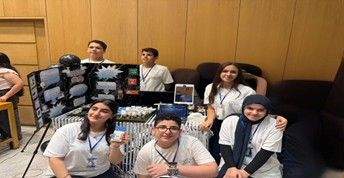 Students pose with their presentation poster and a prototype of their project.