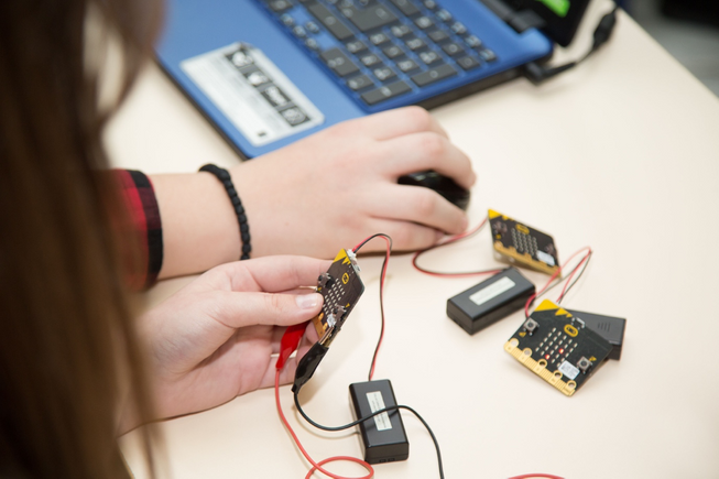 A child sitting at a desk with a micro:bit in hand