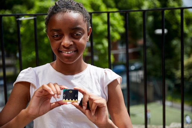 a young girl holding a new micro:bit