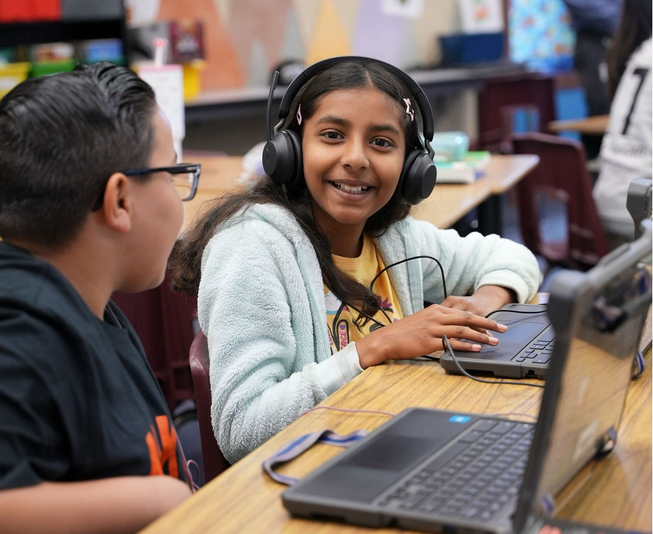 A smiling pupil is coding on a laptop using the micro:bit