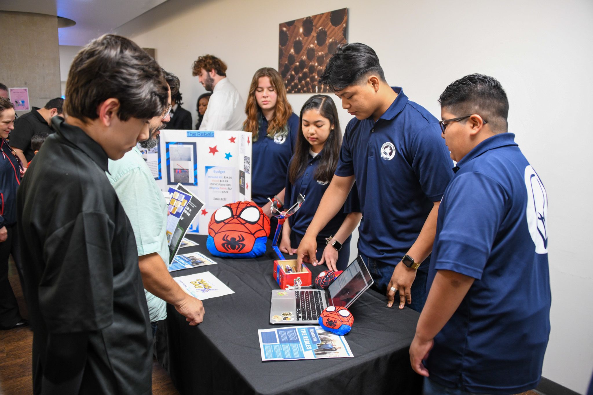 Students stand next to a table with a computer and The Claw prototype.