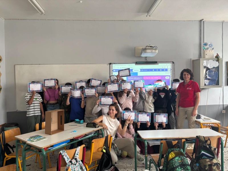 Students pose with their teacher in their classroom in front of a projection showing the code for the project.