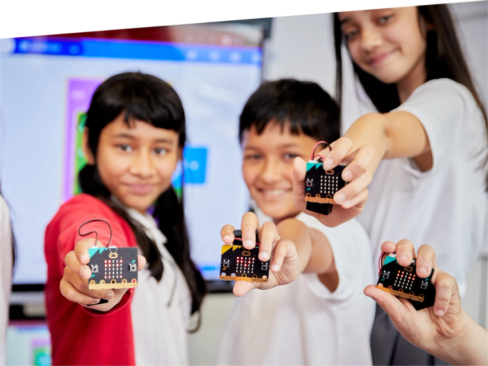 niños  en clase sonriendo  y sosteniendo micro:bits 