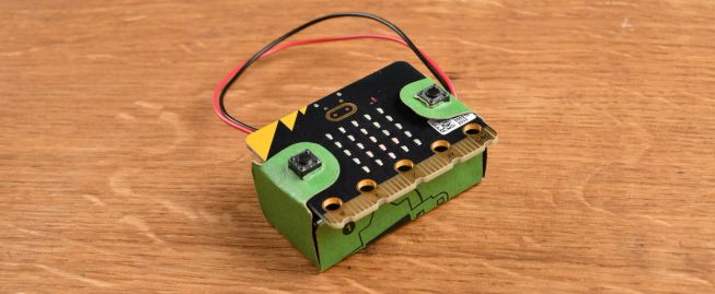 A BBC micro:bit with its cardboard battery pack holder