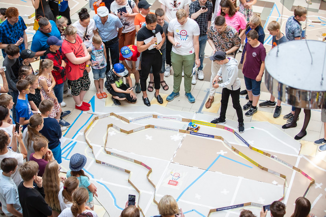 Group of children gathered around a small racing track