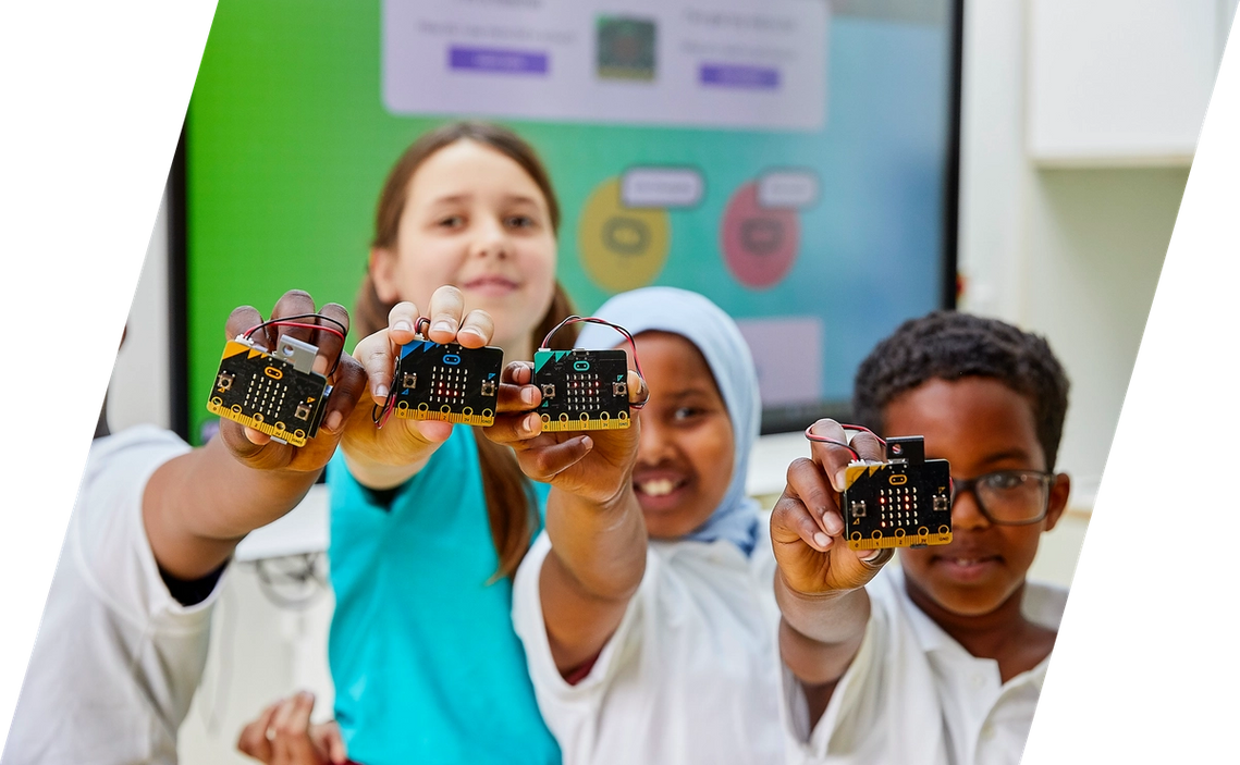Crianças numa aula a sorrir com micro:bits na mão
