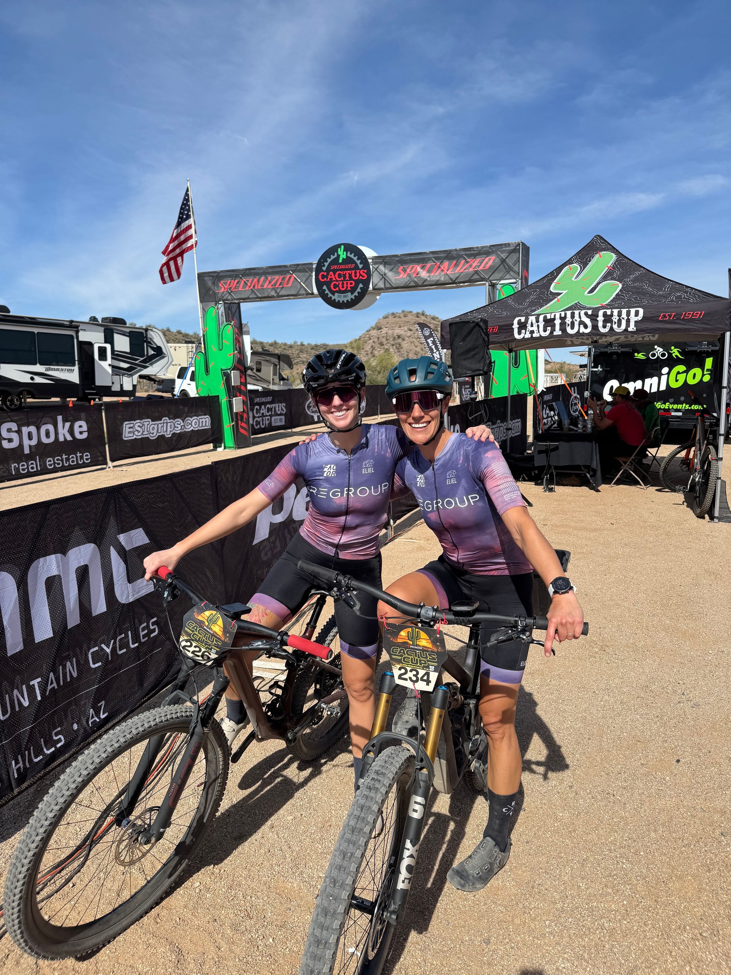 Two riders at the Cactus Cup in front of the sponsor banners