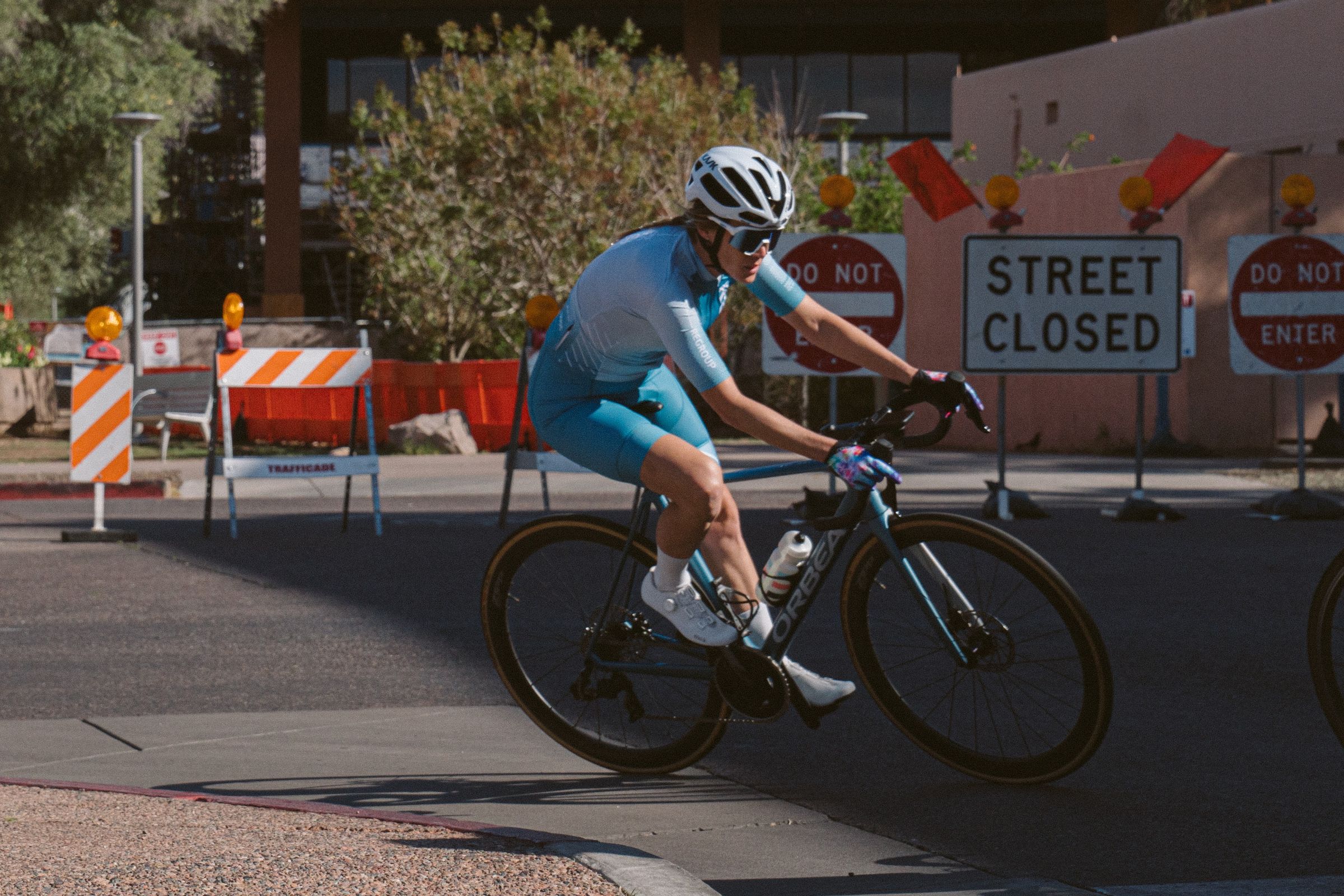 A rider cornering past road-closed signs in a criterium