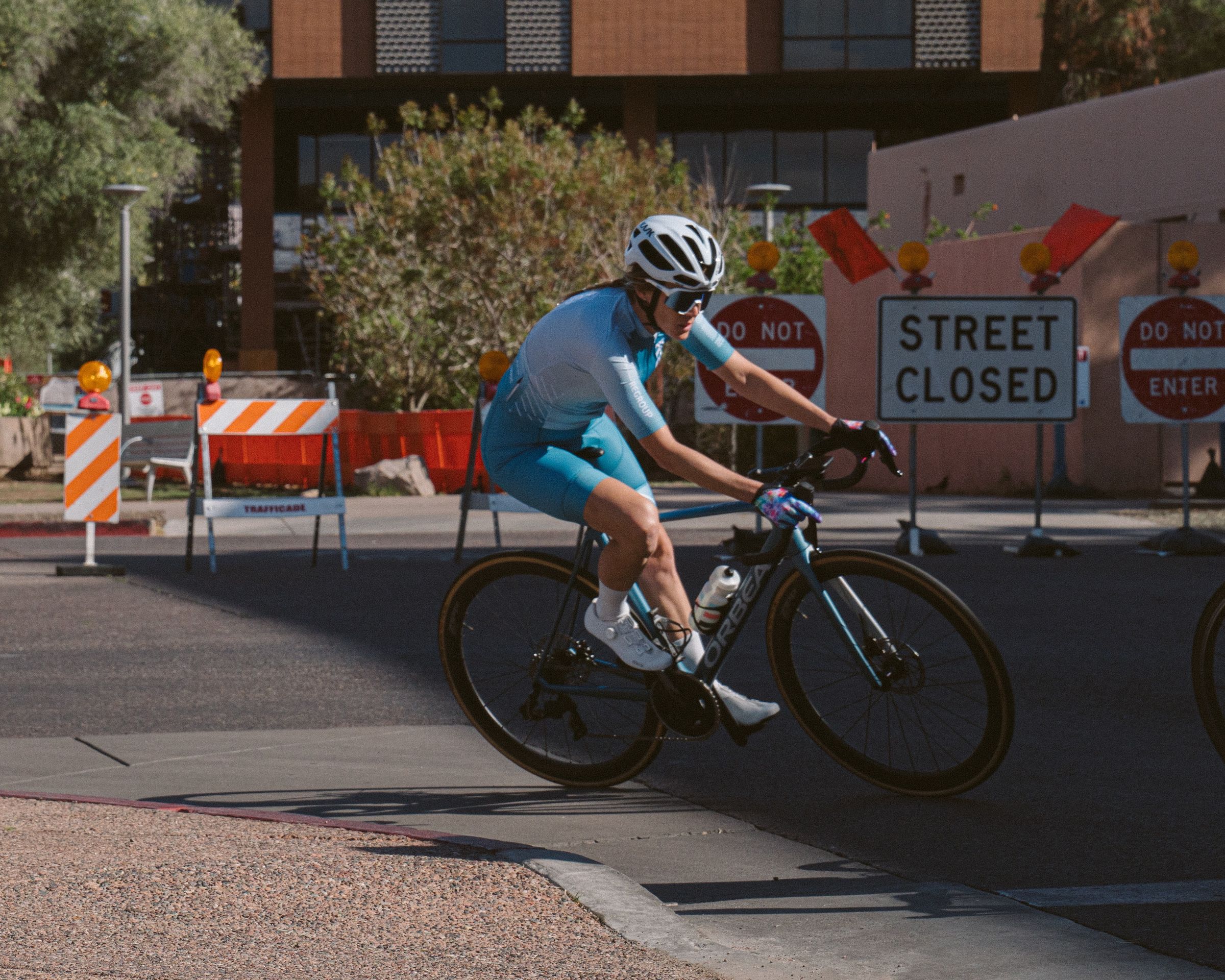 A rider cornering past road-closed signs in a criterium