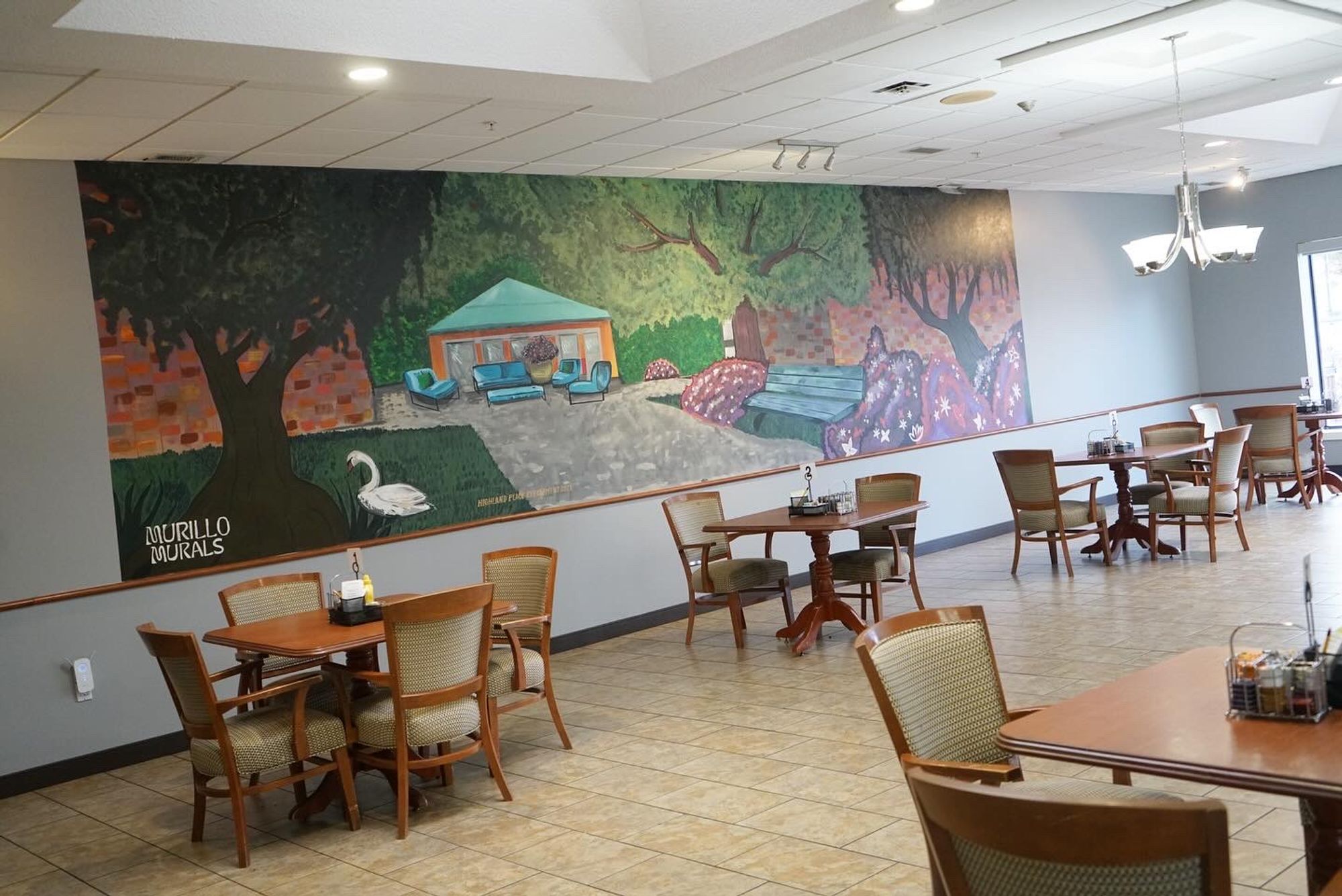 A photo of a mural in a restaurant that features trees, a goose, and a house 