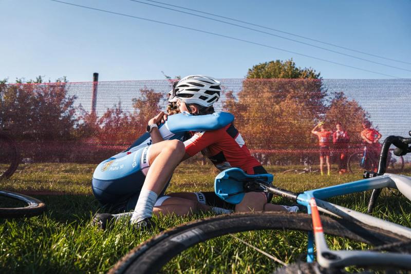 Dva závodníci v objetí na trávě po dojezdu — Cyklokros Chýnov 2026, JANEV Cup, foto Martin Kozojed