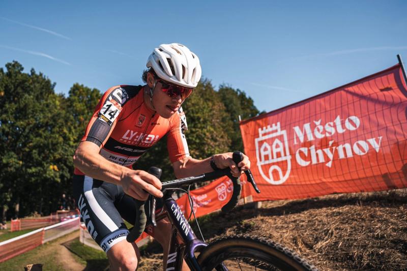 Závodník stoupá s kolem kolem banneru Město Chýnov — Cyklokros Chýnov 2026, JANEV Cup, foto Martin Kozojed