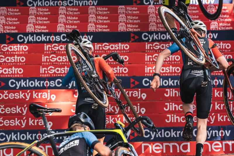 Závodníci vybíhají s koly na ramenou schody — Cyklokros Chýnov 2026, TBC série, foto Martin Kozojed