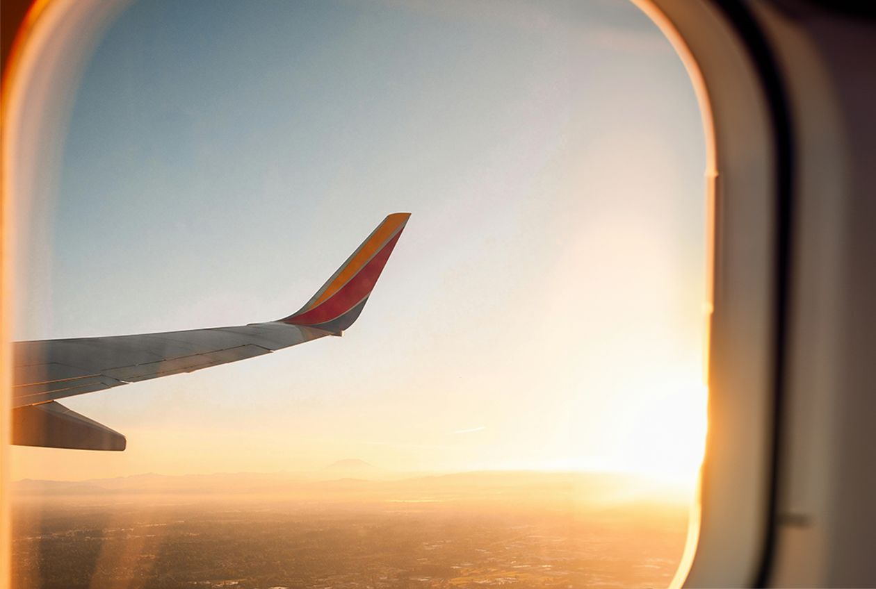 Looking out an airplane window at the plane wing and sunset.