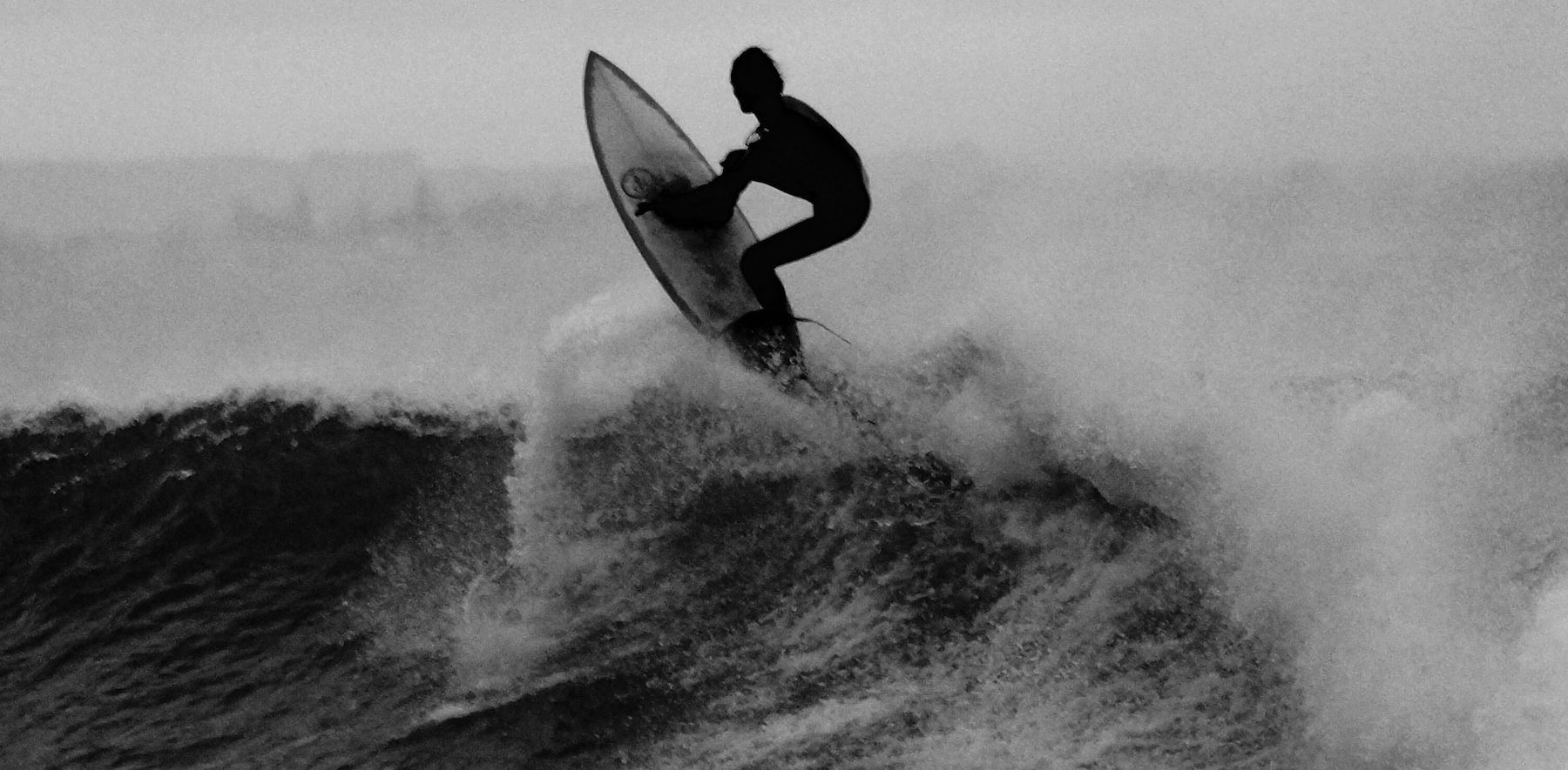 Mustavalkoinen kuva henkilöstä surffaamassa