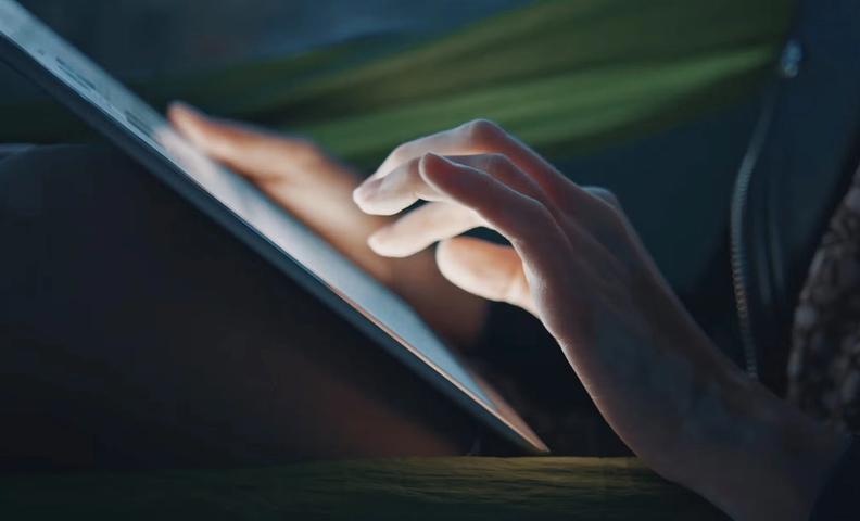 Kädet pitelevät älytablettia ja vasen käsi on koskettamassa näyttöä