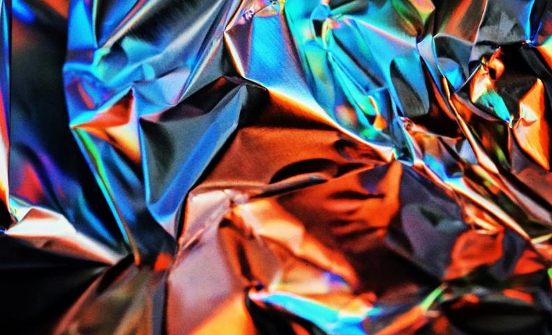 Kuvituskuva, metallin väristä materiaalia, jota on puristettu kasaan