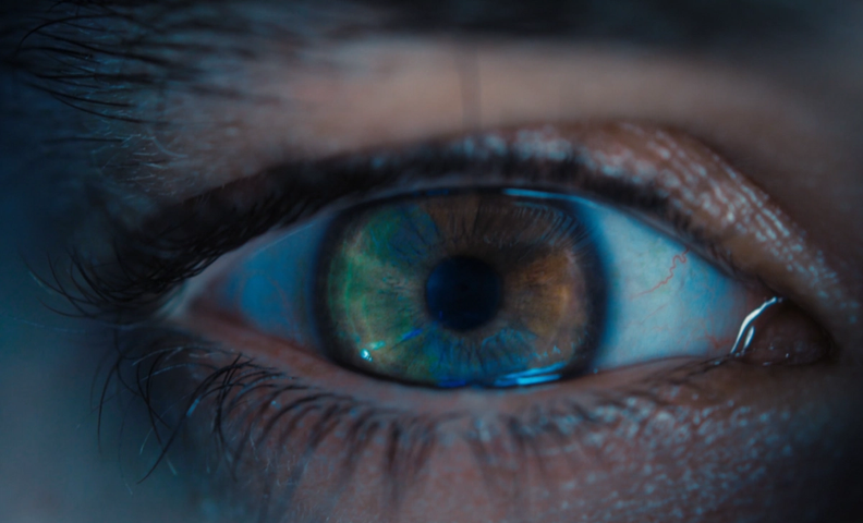 Крупный план глаза человека с ярко-голубой радужной оболочкой.