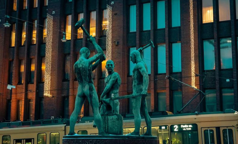 Памятник Kolmen sepän patsas в Хельсинки напротив универмага Стокманн