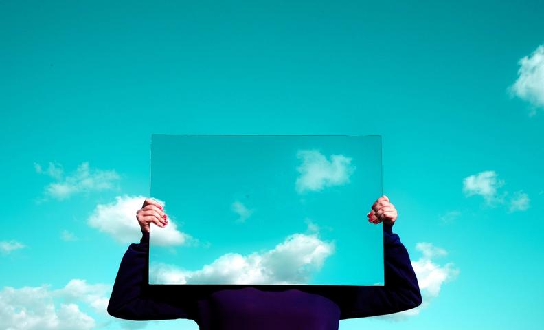 Человек держит в руке квадратный кусок стекла.