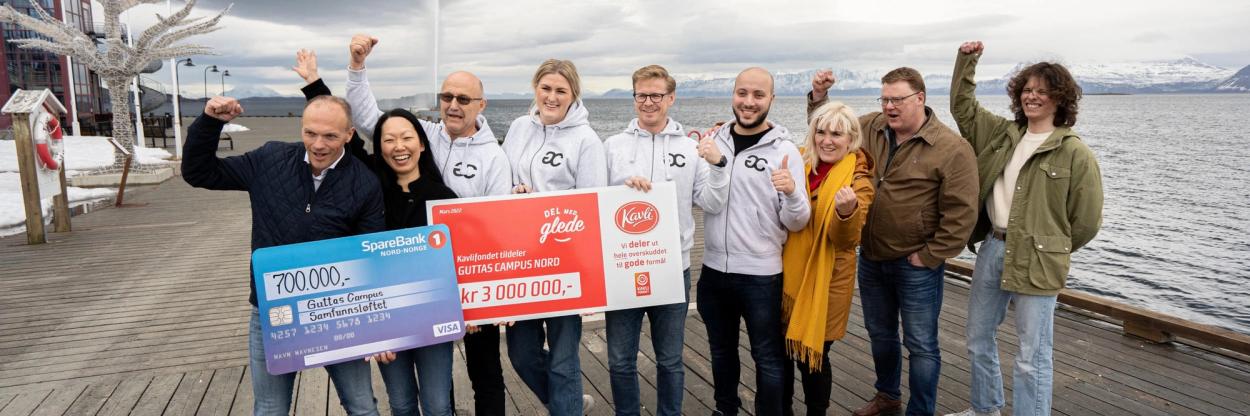 Samarbetspartnerna för Guttas Campus står på rad medan de håller upp checkarna.