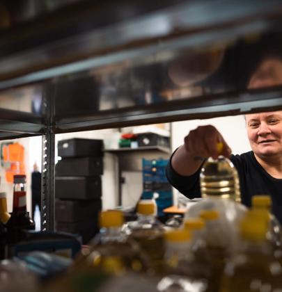 Ansatt i en av Sveriges Matsentraler foran en hylle med matvarer