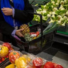 En kund i butiken lägger en ananas i kundkorgen.