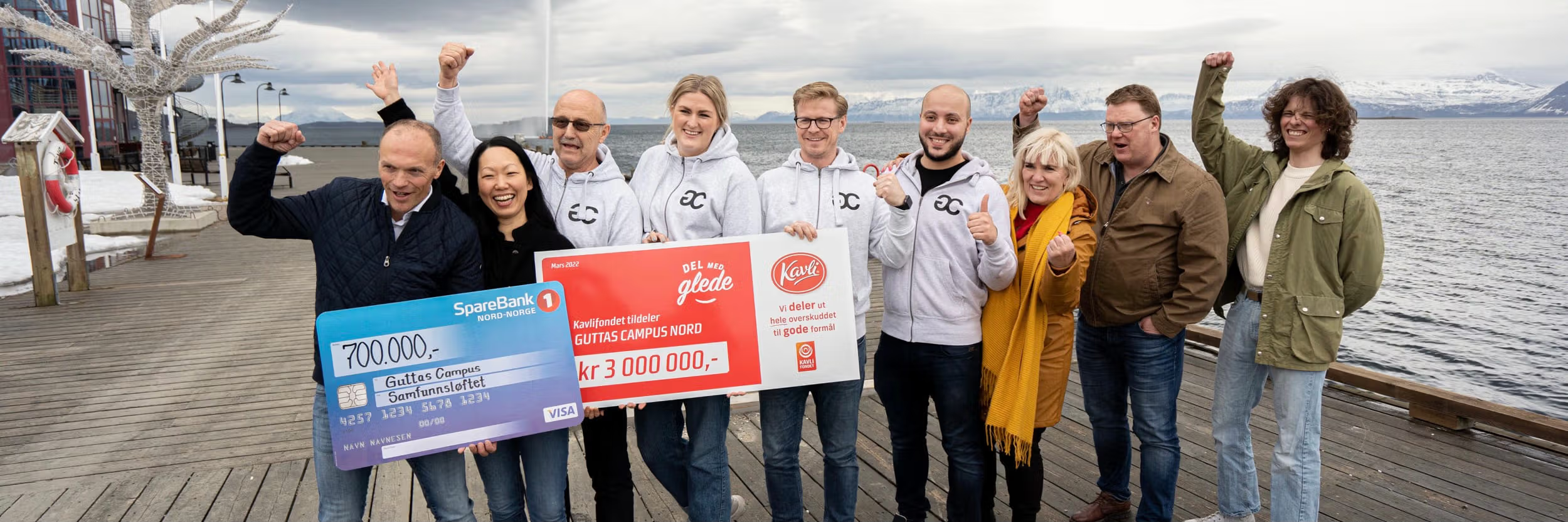 På en brygge i Harstad står representanter for spleiselaget sammen med daglig leder i Guttas Campus og holder oppe gavesjekkene.