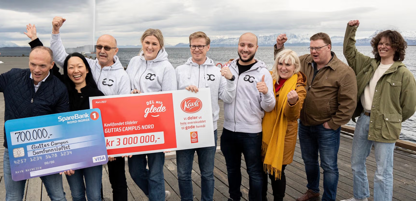 On a pier in Harstad, representatives of the joint funding initiative stand together with the CEO of Guttas Campus, holding up the donation cheques.