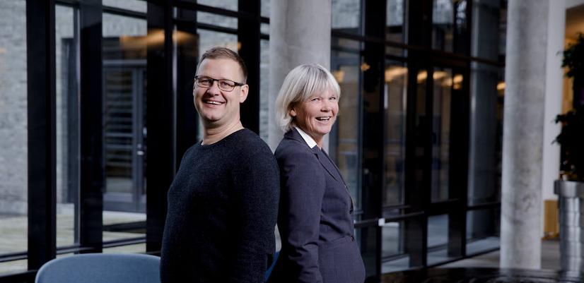 Clinical psychologists Bjarne Hansen and Gerd Kvale stand smiling back to back, facing the camera.