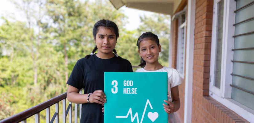 To jenter holder bilde av FNs bærekraftsmål nr 3: God helse