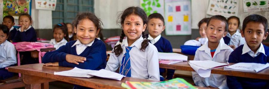A group of children sit in their classroom.